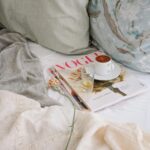 Relaxing morning with coffee and Vogue magazine on a comfortable bed.